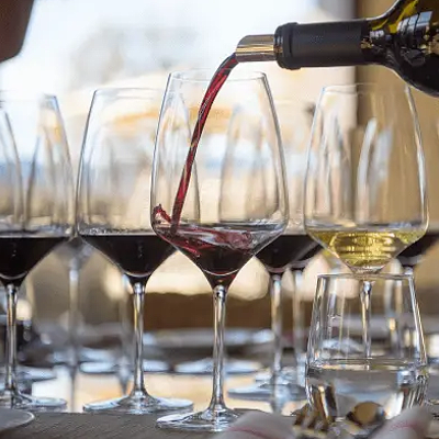 Vino & Vinyl Featured Image Wine glasses with wine being poured in