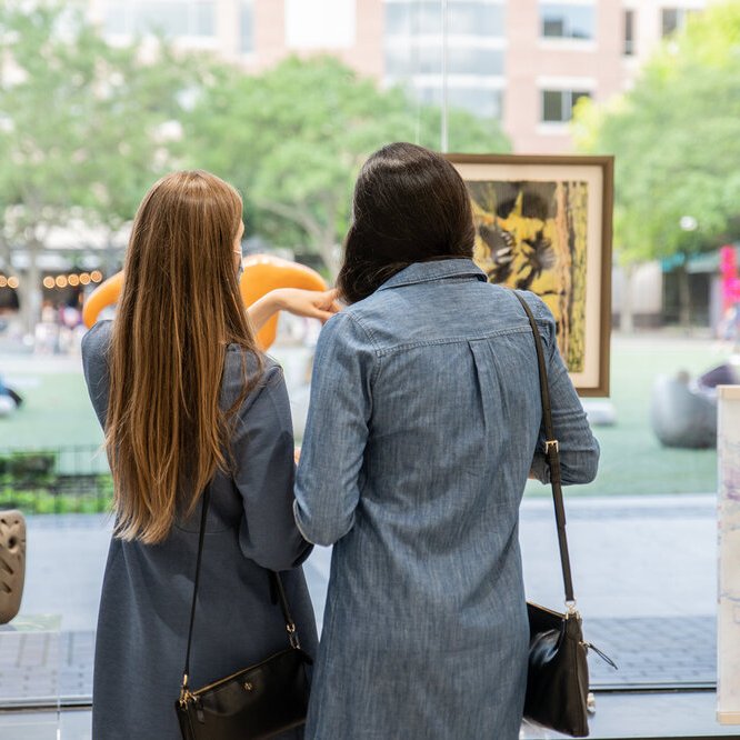 two women looking at a painting