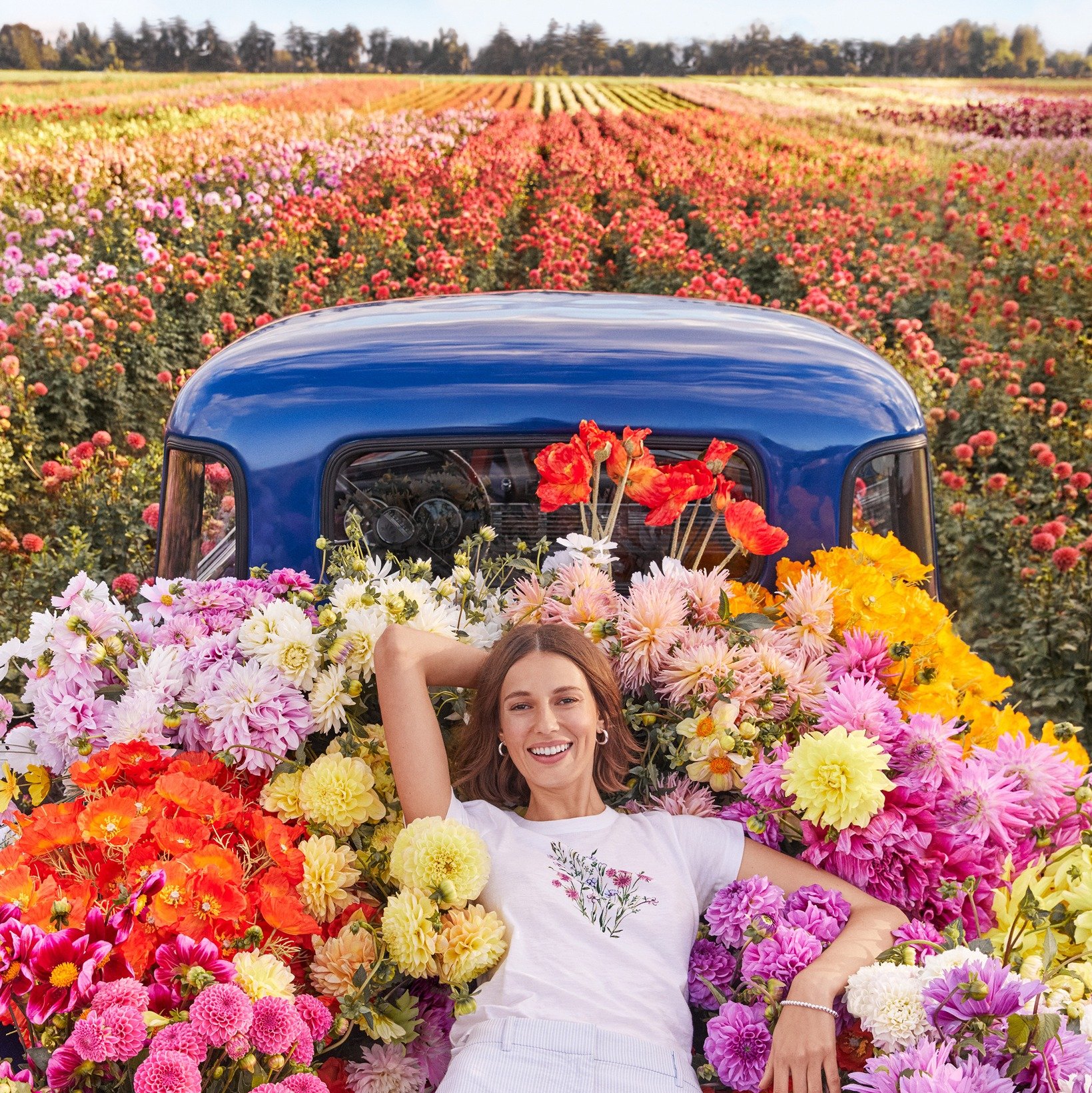 Loft Bed of truck covered in flowers with woman lying on top